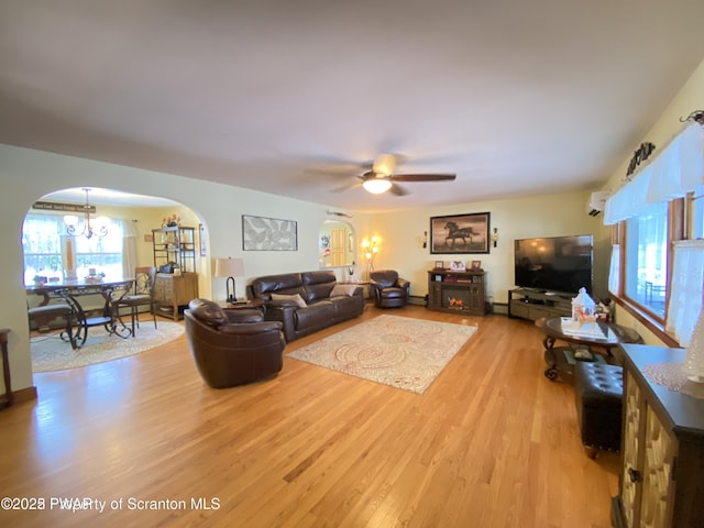 living room with ceiling fan with notable chandelier and light hardwood / wood-style flooring