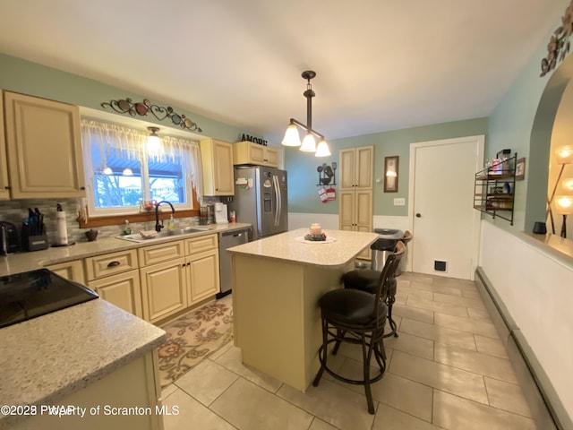 kitchen with a kitchen bar, sink, a center island, hanging light fixtures, and appliances with stainless steel finishes