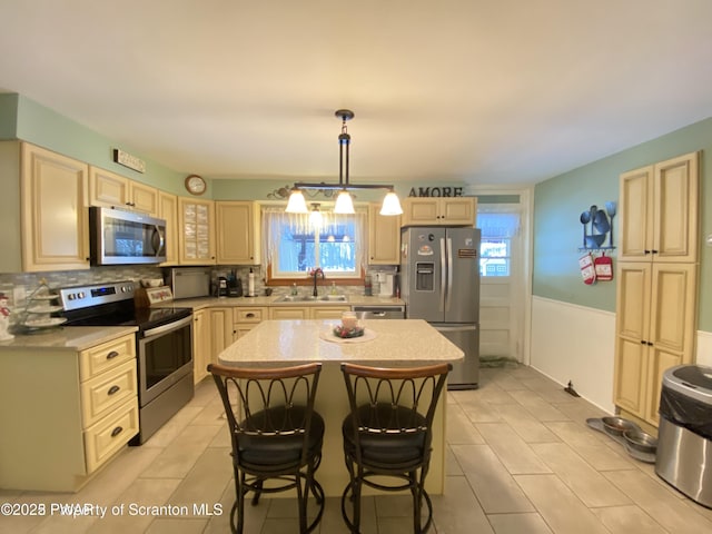 kitchen with appliances with stainless steel finishes, a breakfast bar, pendant lighting, sink, and a center island