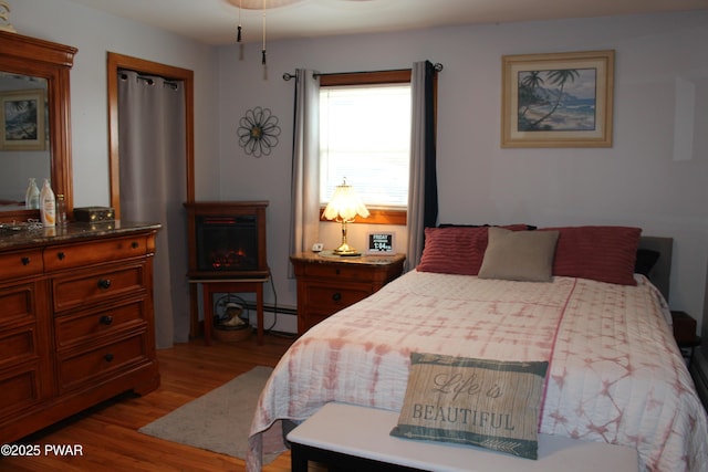 bedroom featuring light hardwood / wood-style floors and a baseboard heating unit