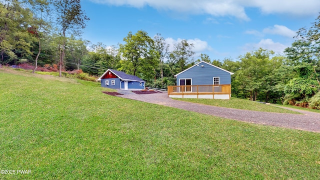 136 Heaters Hill Rd, Matamoras, PA 18336 - view of grassy yard featuring a wooden deck, driveway, view of scattered trees, an outbuilding, and a garage