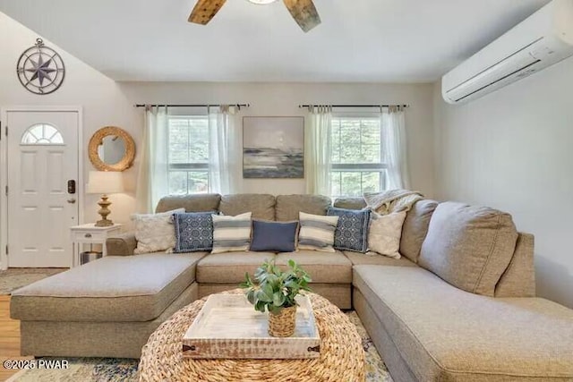 living room with a wealth of natural light, a wall mounted AC, a ceiling fan, and wood finished floors