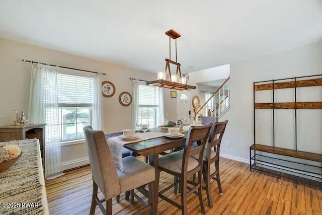 dining space featuring stairs, baseboards, and light wood-type flooring
