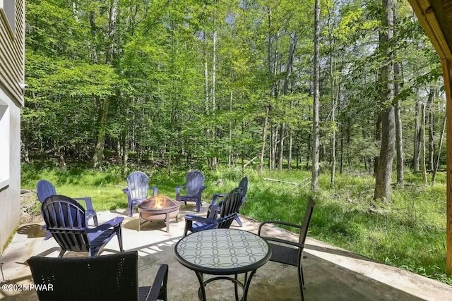 view of patio featuring a forest view and an outdoor fire pit