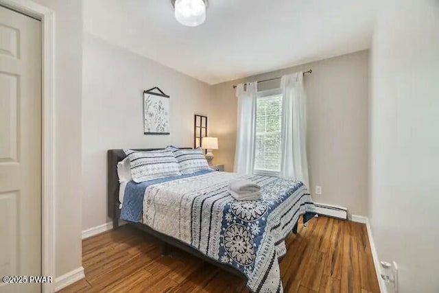 bedroom featuring a baseboard heating unit, baseboards, and wood finished floors