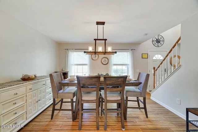 dining area featuring an inviting chandelier, baseboards, stairs, and light wood-style floors