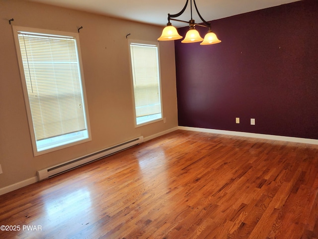 unfurnished room featuring baseboard heating and hardwood / wood-style flooring