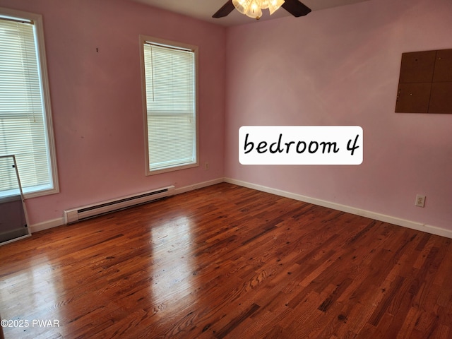 empty room featuring ceiling fan, wood-type flooring, and a baseboard heating unit