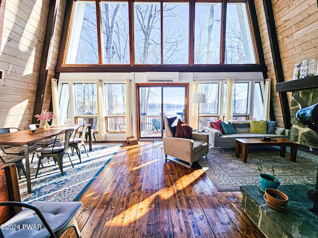 176 Fawn Lake Dr, Hawley, PA 18428 - living area featuring a wall mounted AC, wooden walls, hardwood / wood-style flooring, and a high ceiling