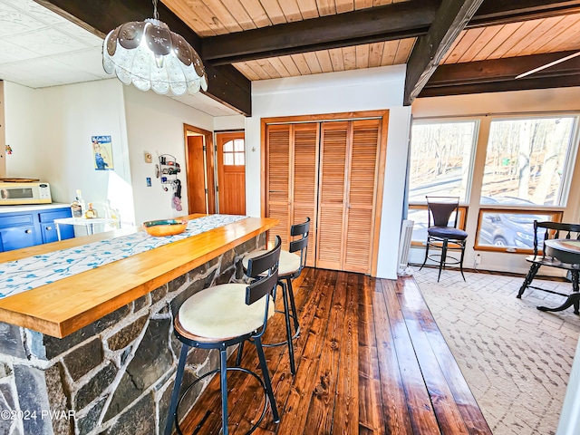 dining room with beam ceiling and dark hardwood / wood-style flooring