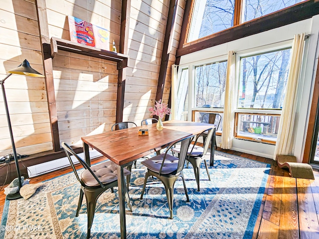 dining room with wooden walls, a towering ceiling, and wood-type flooring