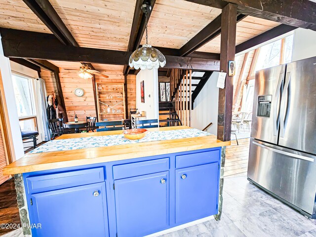 kitchen with wood walls, wood counters, stainless steel fridge, and beam ceiling