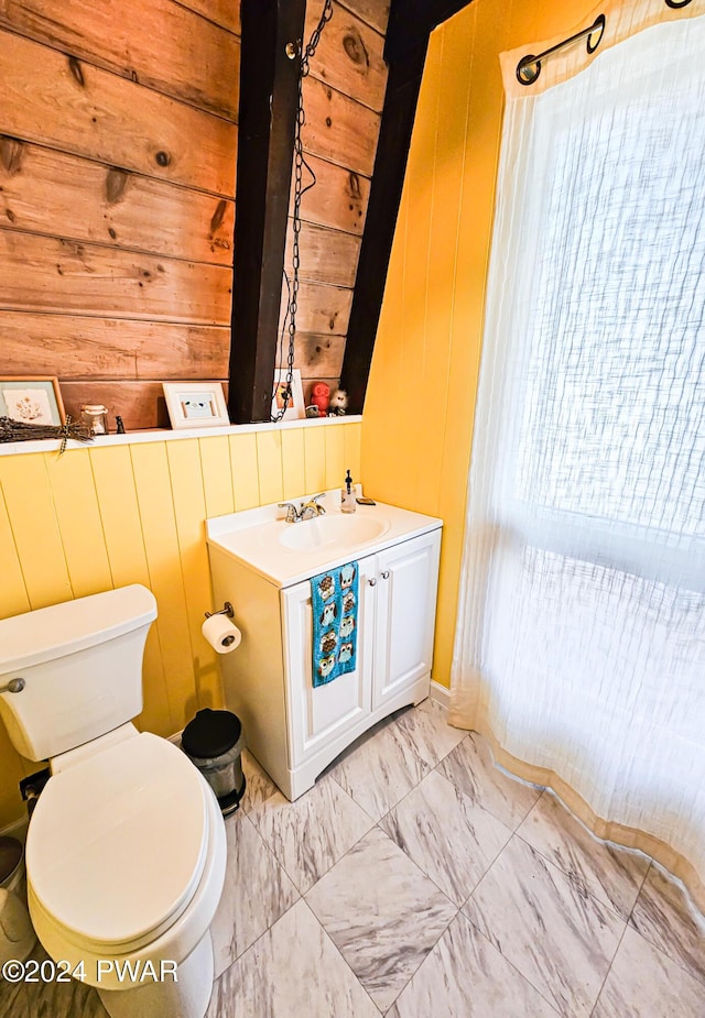 bathroom with vanity, toilet, and wooden walls