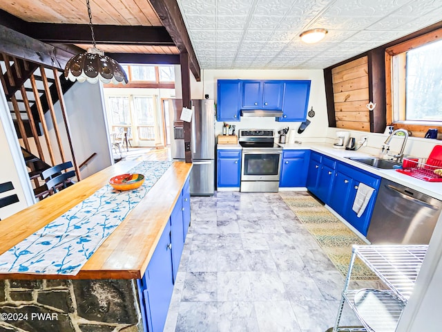 kitchen featuring butcher block counters, sink, blue cabinets, pendant lighting, and appliances with stainless steel finishes