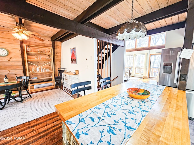 dining area with beam ceiling, wooden ceiling, ceiling fan, and wooden walls