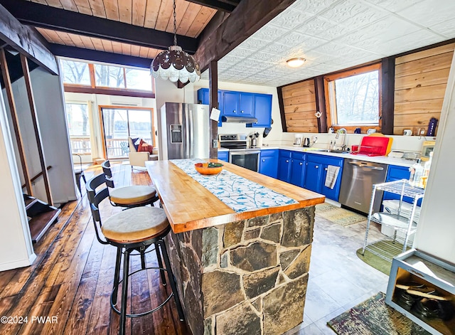 176 Fawn Lake Dr, Hawley, PA 18428 - kitchen with blue cabinets, appliances with stainless steel finishes, a sink, beamed ceiling, and a kitchen bar