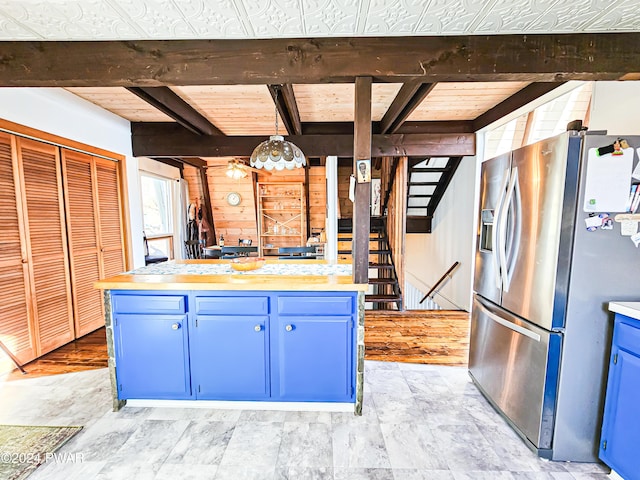 kitchen featuring beam ceiling, blue cabinetry, stainless steel fridge, decorative light fixtures, and wood ceiling