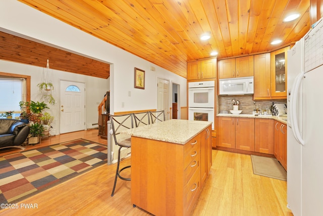 kitchen featuring white appliances, a center island, a kitchen bar, tasteful backsplash, and light hardwood / wood-style floors