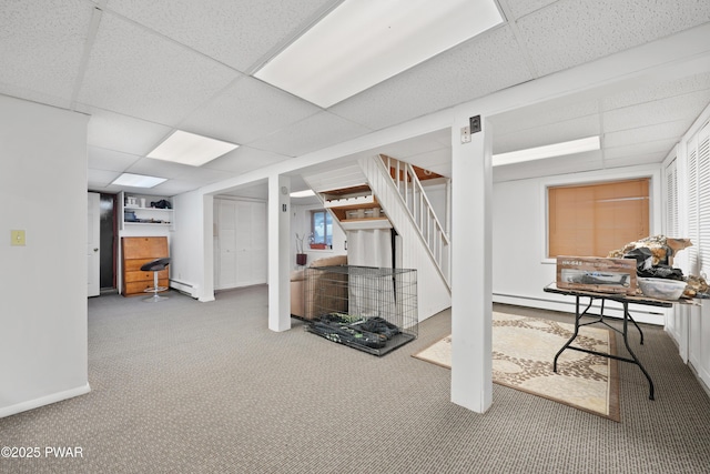 basement featuring a drop ceiling, a baseboard heating unit, and carpet