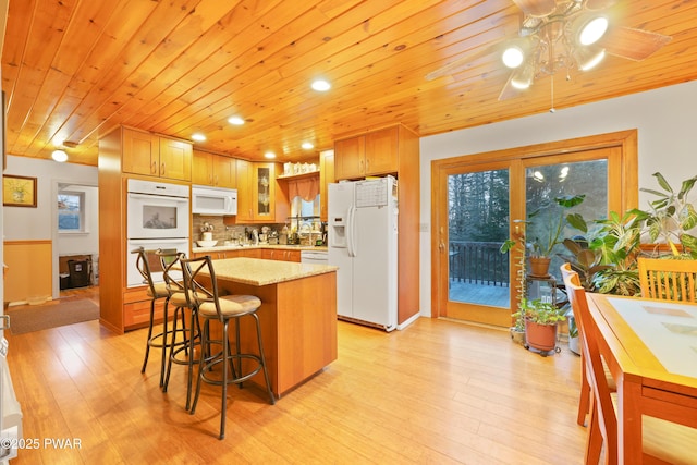 kitchen featuring white appliances, a center island, wood ceiling, decorative backsplash, and ceiling fan