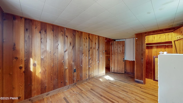 unfurnished room with light hardwood / wood-style floors and wood walls