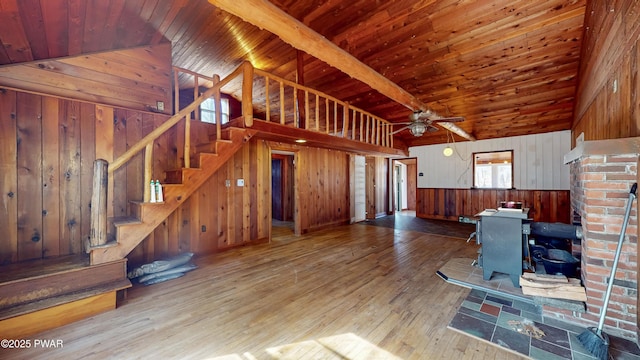 living room featuring light hardwood / wood-style flooring, ceiling fan, wooden walls, wooden ceiling, and a wood stove