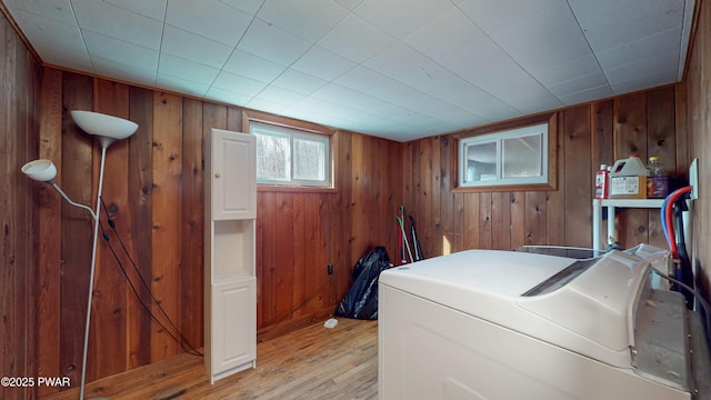 clothes washing area featuring washing machine and dryer, wood walls, and light hardwood / wood-style flooring