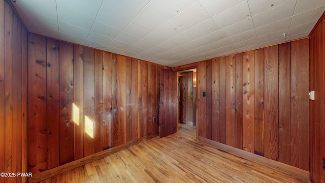 empty room with wood walls and light wood-type flooring