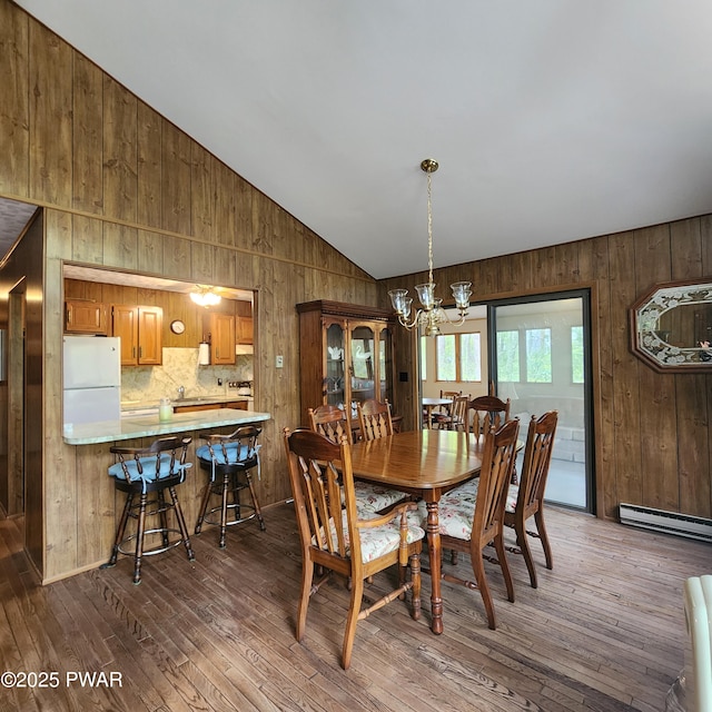 802 Placer Ct, Lords Valley, PA 18428 - dining space with a chandelier, wood walls, dark wood finished floors, vaulted ceiling, and a baseboard heating unit