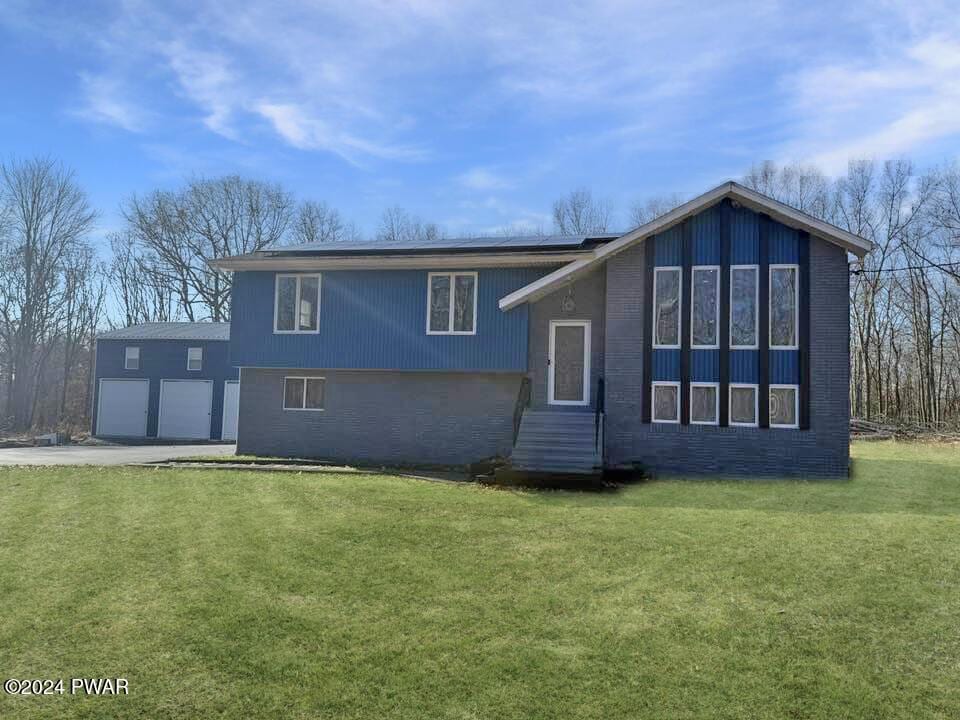 rear view of house featuring a lawn and a garage