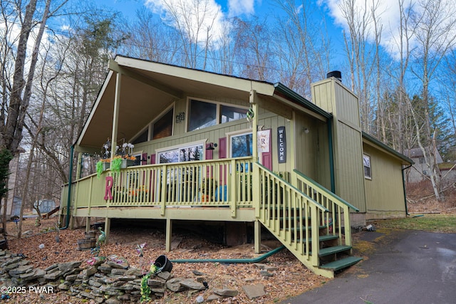 back of house with a chimney and a porch