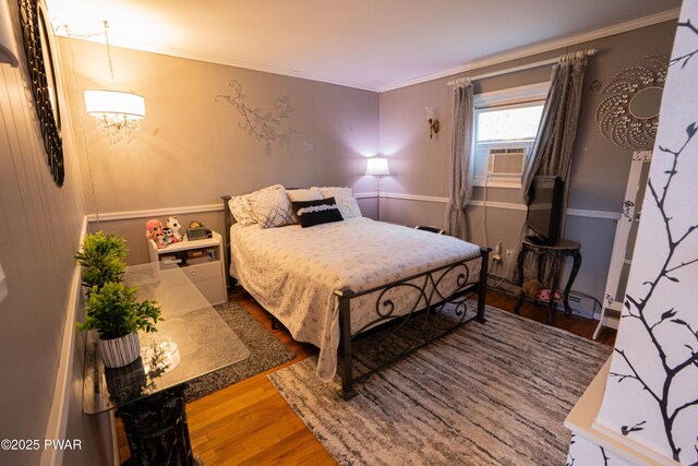 bedroom featuring crown molding, cooling unit, and wood finished floors