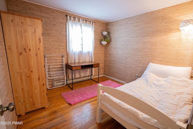 bedroom featuring baseboard heating and wood finished floors