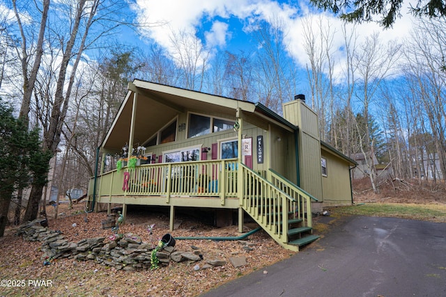 view of front of house featuring covered porch, driveway, and a chimney