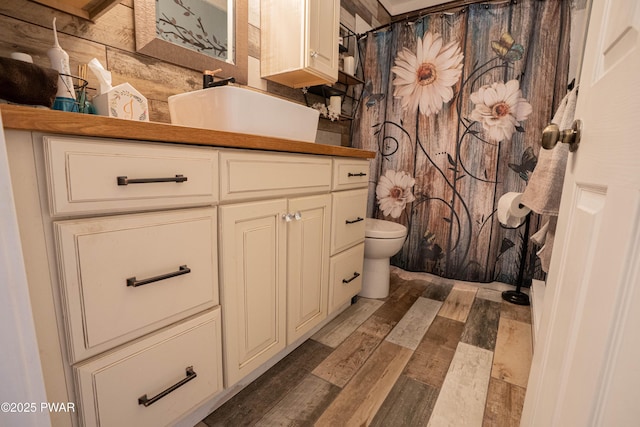 bathroom with wood finished floors, vanity, toilet, and curtained shower