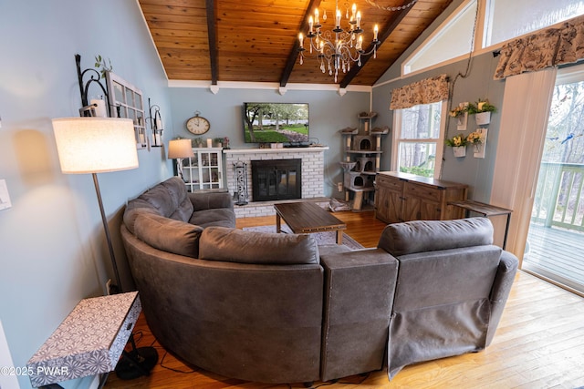 living room featuring a wealth of natural light, a fireplace, vaulted ceiling with beams, and wood finished floors