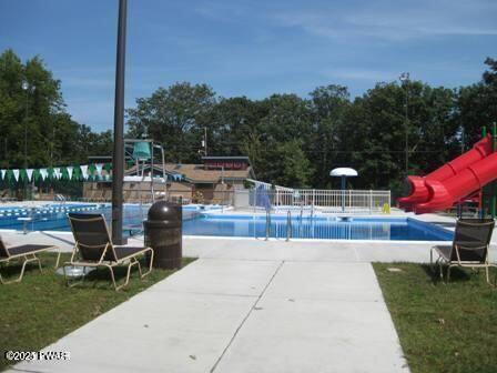 community pool with a water slide, a patio area, and fence