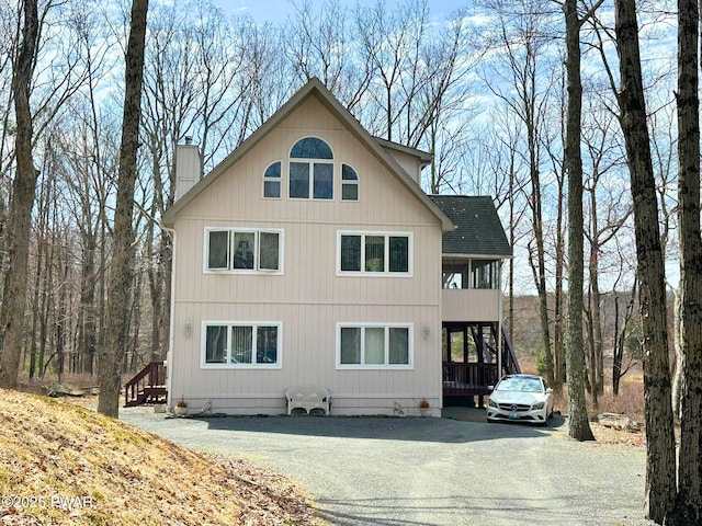 view of home's exterior featuring a chimney, stairway, and aphalt driveway