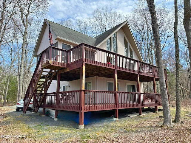rear view of property with a wooden deck and roof with shingles