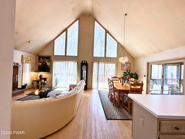 living area with a healthy amount of sunlight, high vaulted ceiling, and light wood-type flooring