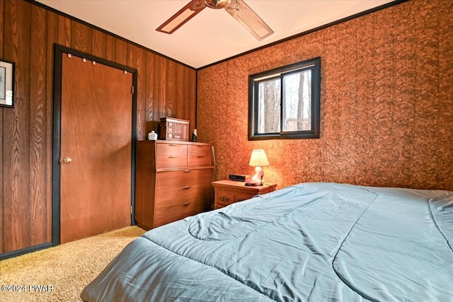 carpeted bedroom with wooden walls, ceiling fan, and crown molding