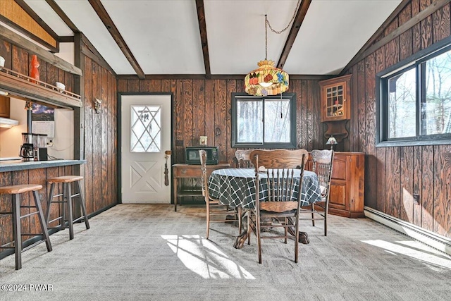 carpeted dining space featuring lofted ceiling with beams and wood walls