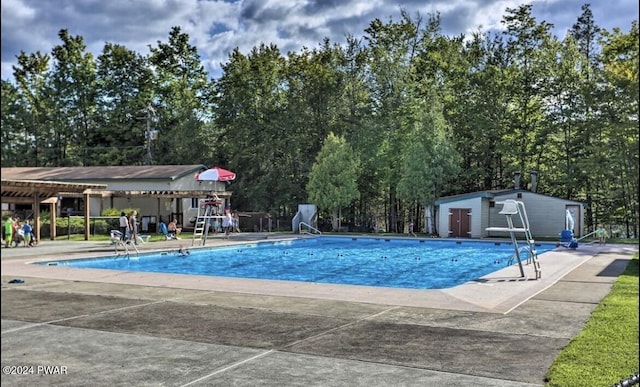 view of swimming pool featuring an outbuilding and a patio