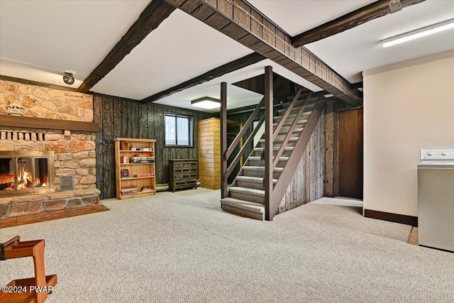 basement featuring washer / clothes dryer, wood walls, a stone fireplace, and carpet