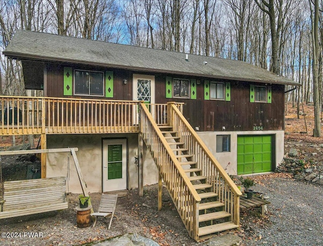 back of property featuring a garage and a wooden deck