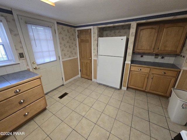 kitchen featuring tasteful backsplash, tile counters, white fridge, and light tile patterned floors