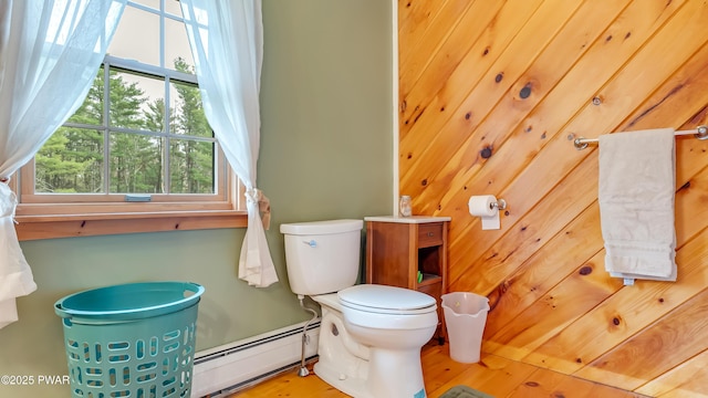 half bathroom featuring plenty of natural light, baseboard heating, and toilet