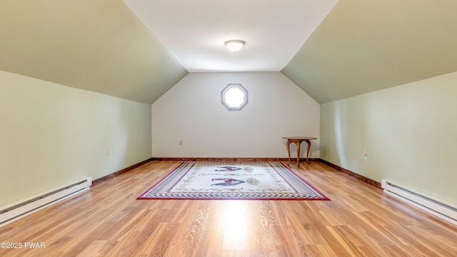 additional living space with baseboards, a baseboard radiator, vaulted ceiling, and light wood-type flooring