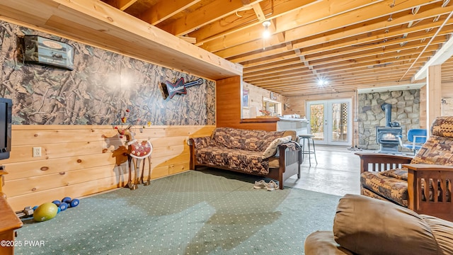 below grade area with french doors, a wood stove, and wooden walls