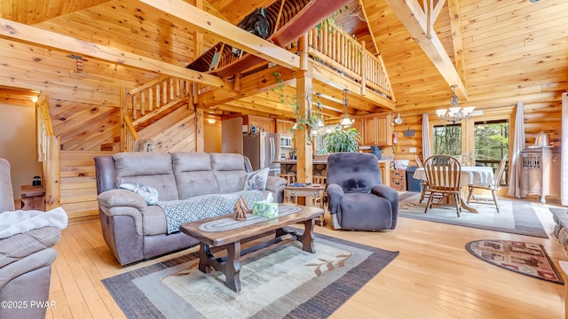 living room featuring an inviting chandelier, light wood-style flooring, stairs, and beamed ceiling
